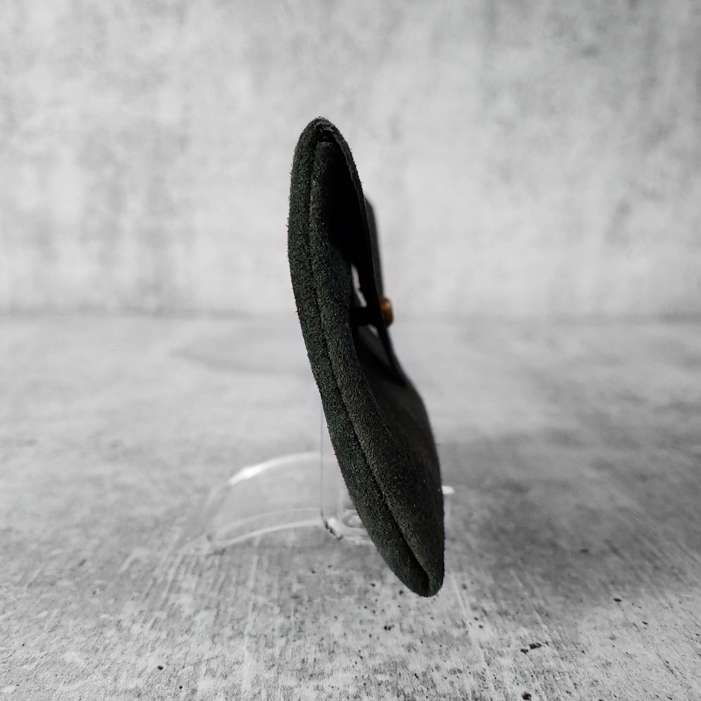 Side view of "soft leather card holder" in rosemary against a concrete background.