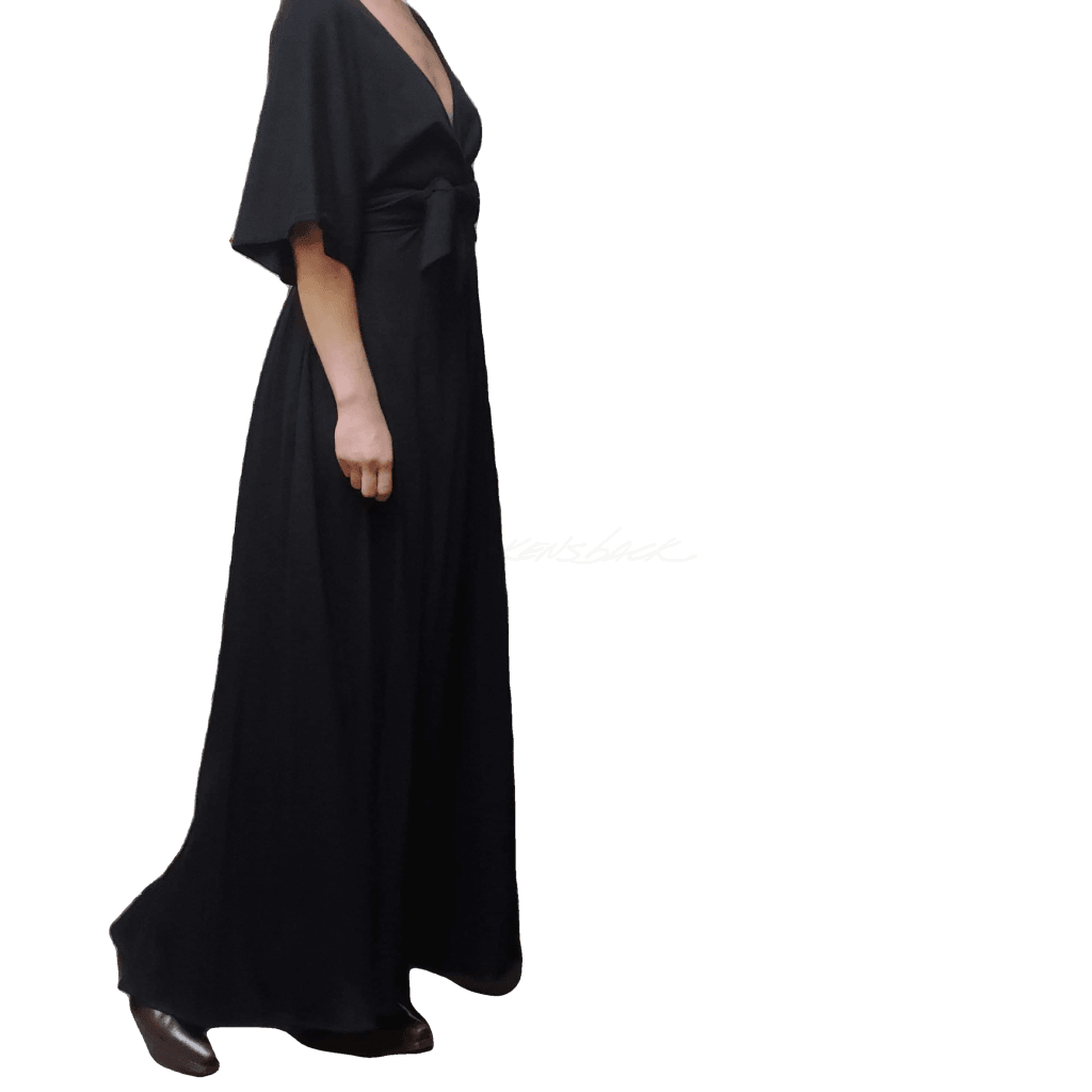 Partial side view of model wearing McCULLOUGH Carnaby Maxi dress in black knit jersey with matching waist tie.