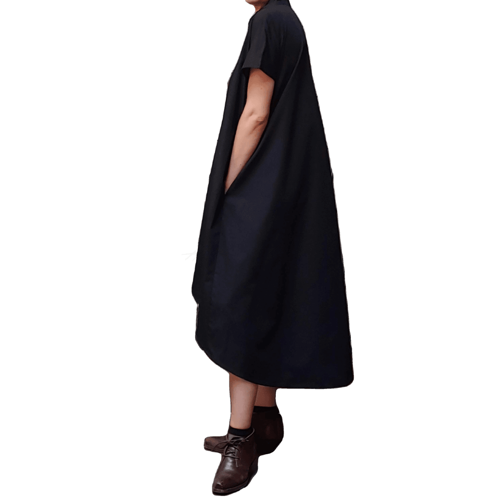 Side view of model in McCULLOUGH High Low Henley Tunic in black pima cotton at Harkensback. Hand is in pocket.