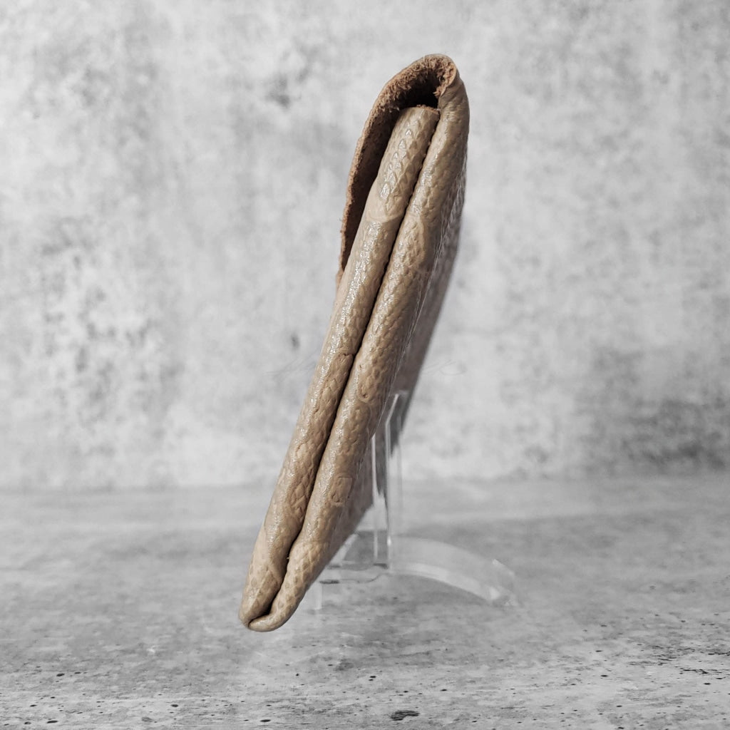 Side view of "leather clutch triangle" in dovetail against a concrete background.