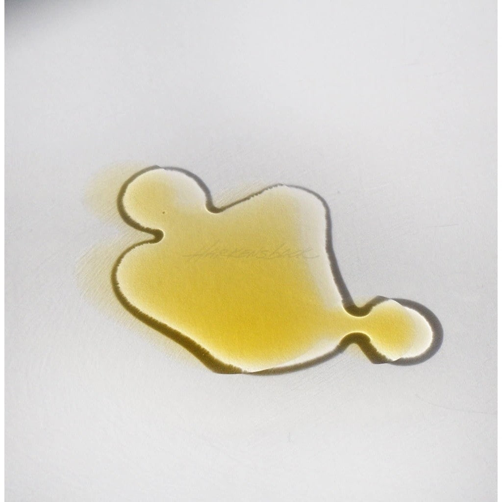 Amber colored NOTO Mini Deep Serum product smudged against white surface to showcase consistency and pigment.
