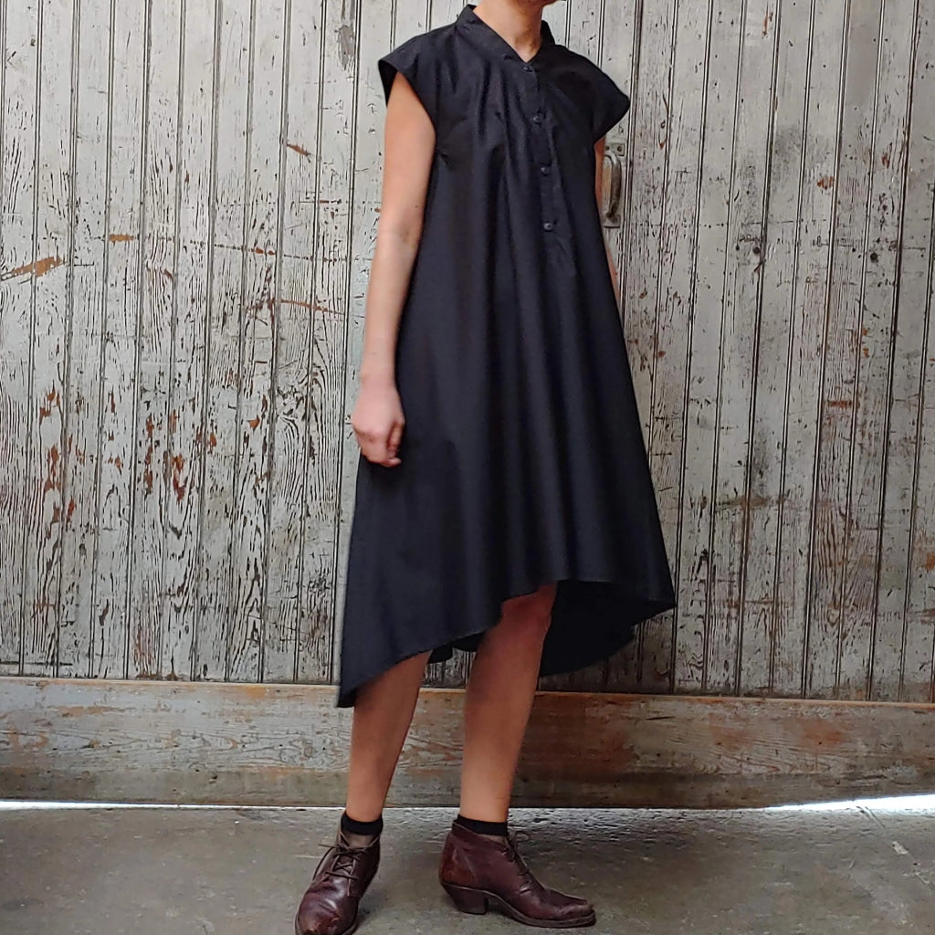 Model wearing McCULLOUGH button down Rambla swing dress in black poplin cotton at Harkensback. Features nehru collar.