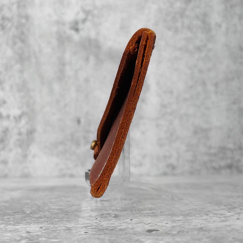 Side view of "slim leather wallet" in kodiak brown against a concrete background.