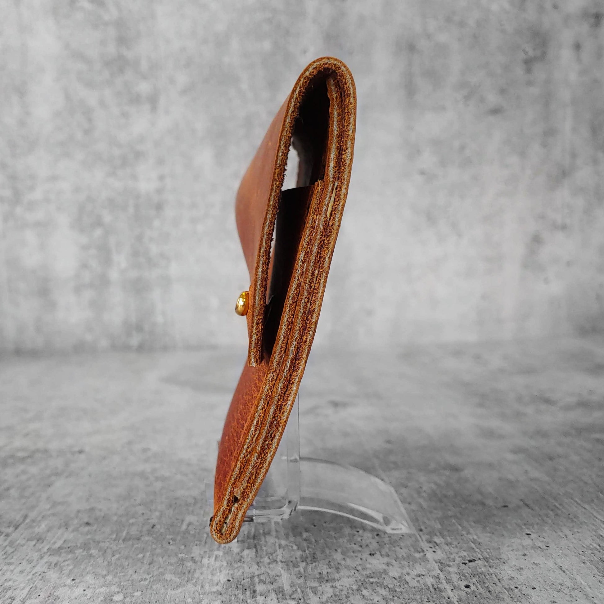Side view of "soft leather wallet right" in pecan brown against a concrete background.