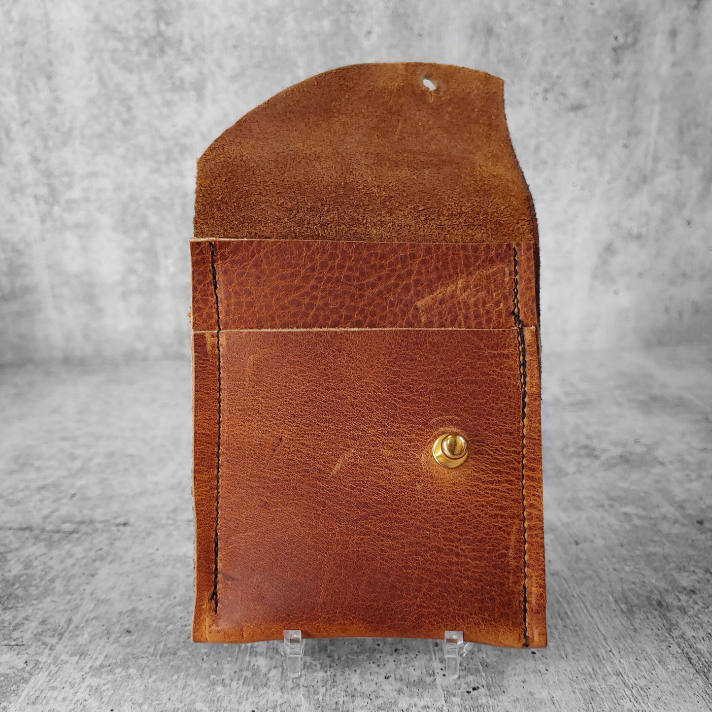 Open, front facing view of "soft leather wallet right" in pecan brown against a concrete background. Pockets visible.
