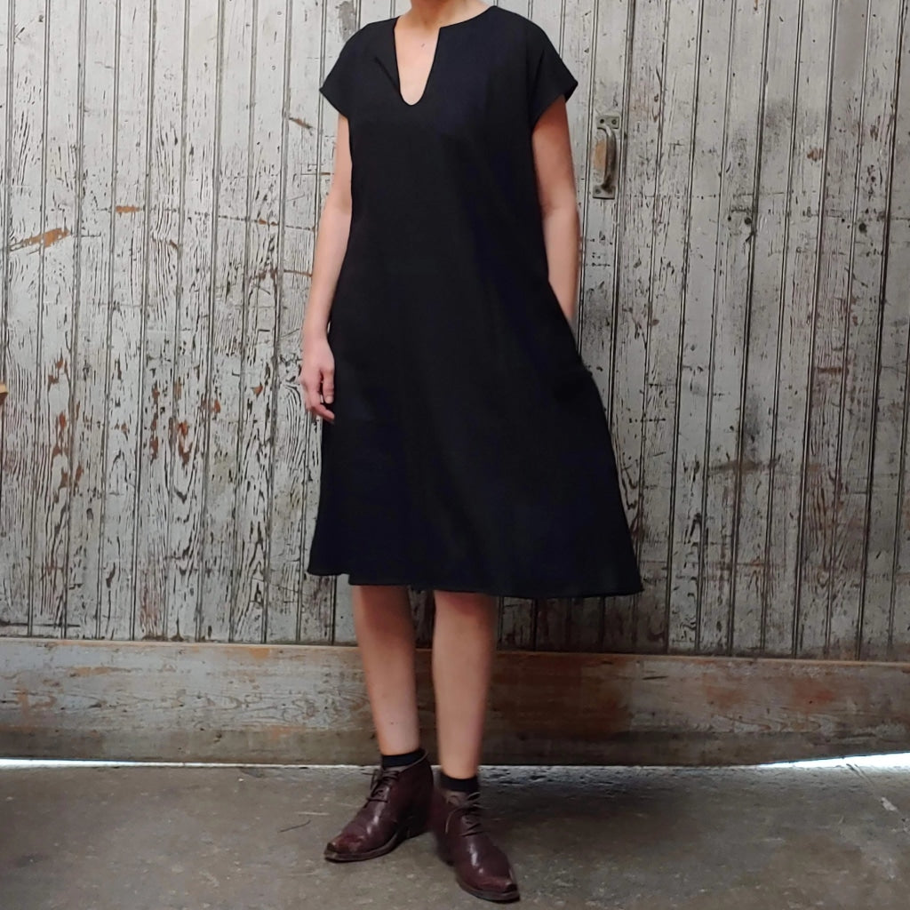 Model wearing McCULLOUGH Morian Midi swing dress in black linen at Harkensback. Hand is in pocket.