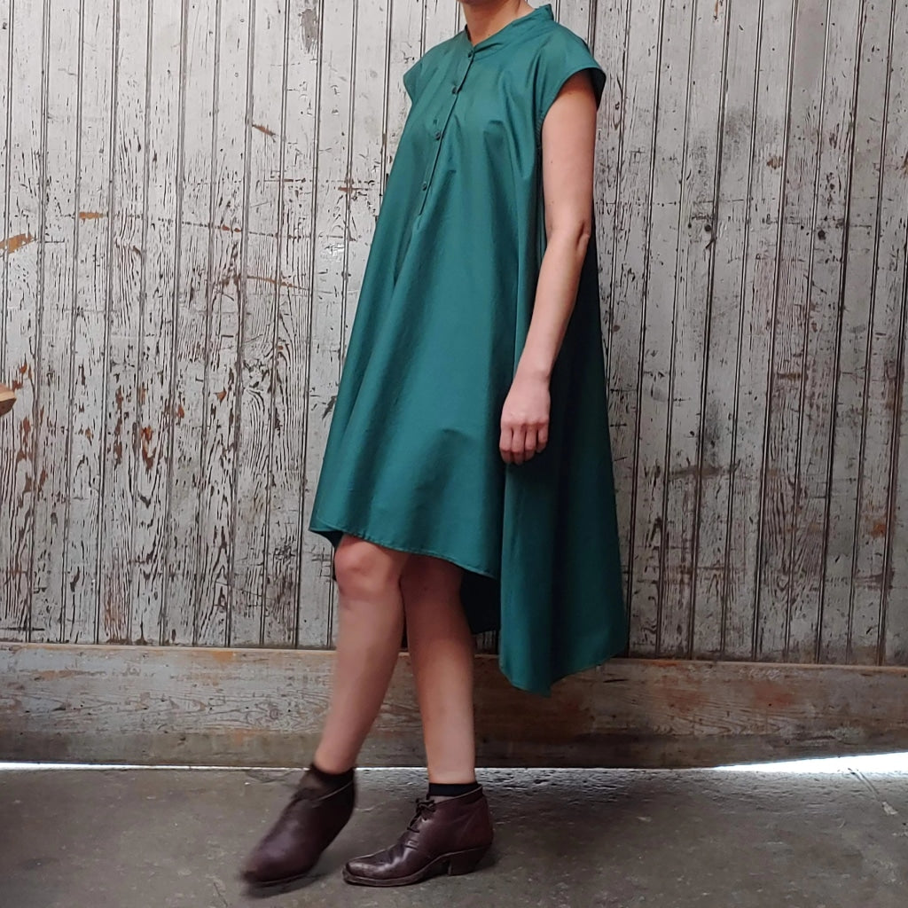 Side view of model wearing McCULLOUGH button down Rambla swing dress in emerald poplin cotton at Harkensback.