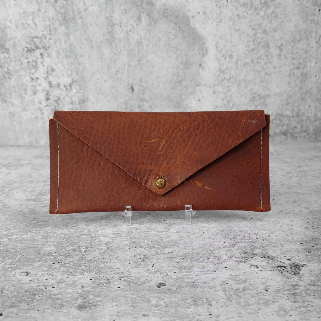 Front facing view of "slim leather wallet" in kodiak brown against a concrete background.